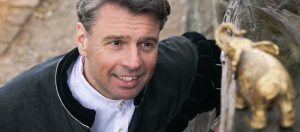 Erzaehler schaut auf einen kleinen Miniatur-Elefanten